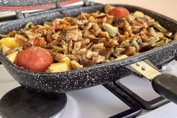 A mixture of meat and vegetables is cooking in a modern pressure cooker closed type on the gas stove