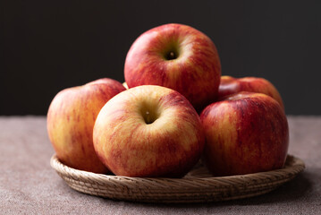 Red apple fruit (Envy apple) in basket on brown fabric with black background