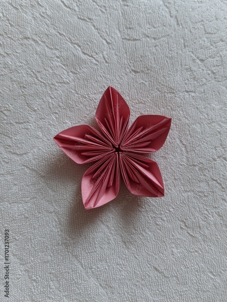 Poster Crafting a Delicate Pink Origami Flower With Intricate Folding Techniques Displayed on a Textured Surface