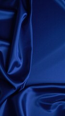 Fototapeta premium A luxurious blue silk fabric drapes elegantly, showcasing its smooth texture and rich sheen, reflecting light beautifully in soft folds.