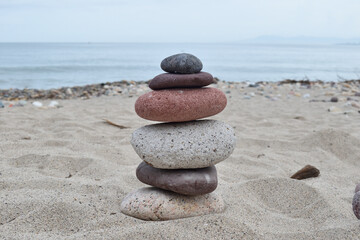 A serene stack of colorful stones placed on the sandy beach, with the ocean in the background in Puerto Vallarta, Jalisco