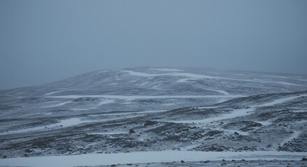 Snowy landscape with rolling hills under a cloudy sky winter weather