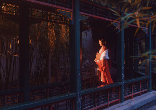 Woman in traditional red hanfu admiring the serene outdoor scenery at sunset. - Powered by Adobe