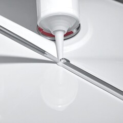 Close-up view of sealant being applied to a smooth, white surface.