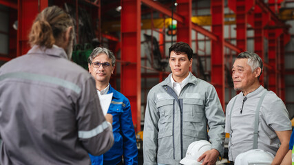 Team engineers and foreman gather for a meeting at the factory machines. Industry workers join together for collaboration and success.