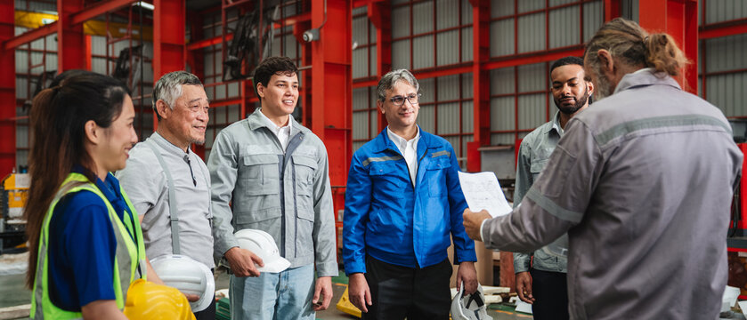 Team engineers and foreman gather for a meeting at the factory machines. Industry workers join together for collaboration and success.