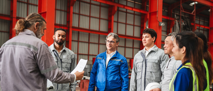 Team engineers and foreman gather for a meeting at the factory machines. Industry workers join together for collaboration and success.