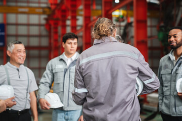 Team engineers and foreman gather for a meeting at the factory machines. Industry workers join together for collaboration and success.
