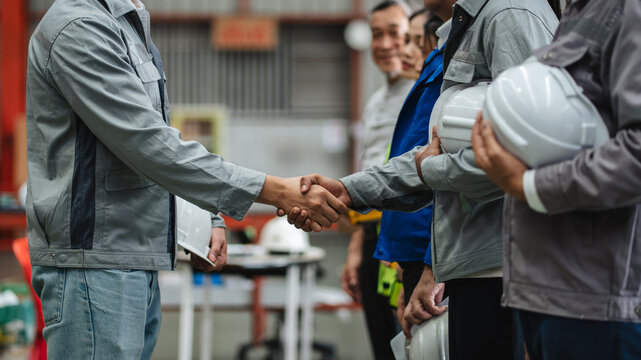 Team engineers and foreman stack hand and shake hands to show success at factory machines. Worker industry join hand for collaboration.