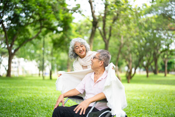 Fototapeta premium An adult man with a disability in wheelchair with a woman in a summer park .The woman and the man look at each other happily. Concept of support for disabled people.