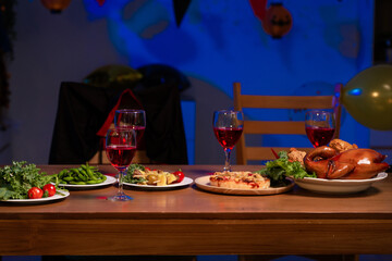 A cozy dinner table set with vibrant dishes, red wine glasses, and warm lighting, symbolizing togetherness, comfort, and the joy of sharing delicious food in a relaxed, festive atmosphere, no people.