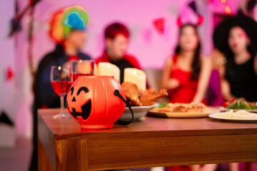 A lively Halloween party table featuring glowing pumpkin decor, festive food, and friends in...