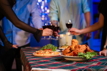Happy friends celebrate together at home party, clinking wine glasses and sharing delicious food. The joyful moment reflects lifestyle, friendship, laughter, festive celebration in warm and colorful