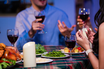 Happy friends celebrate together at home party, clinking wine glasses and sharing delicious food. The joyful moment reflects lifestyle, friendship, laughter, festive celebration in warm and colorful