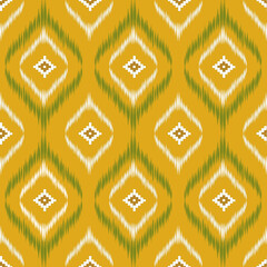Geometric ikat pattern with diamond motifs in green and white on a warm yellow background, creating a bold and traditional textile design.