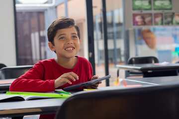 In school, smiling boy using tablet in classroom, engaging with technology, copy space
