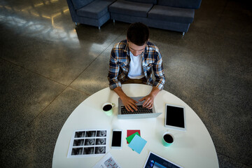Laptop, tablet and smartphone are resting on round white table in modern lounge, with paper cups