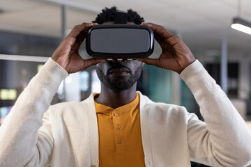 African American man holding VR headset inside modern office with glass partitions, copy space