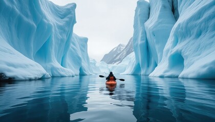 Kayaker paddles through a narrow channel between towering blue ice walls