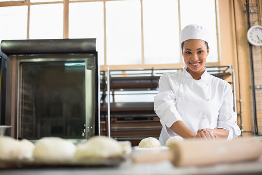African American woman kneading dough with rolling pin on steel table in bakery, copy space