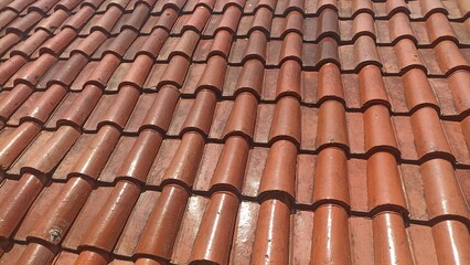Close-up of Wavy Red Roof Tiles. Detailed Surface of Ceramic Building Material with Sunlight and Shadows. Construction Background