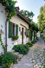 Fototapeta premium Charming cobblestone street passing by picturesque white houses with green shutters in the old town of Plovdiv