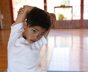 Young boy stretching arms in gym, focusing on exercise and flexibility, copy space