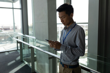 Businessman in office corridor using smartphone, concentrating on important tasks, copy space