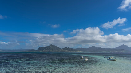 Tourist motorboats are anchored in the turquoise ocean. Corals are visible through clear water....