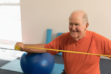 Elderly man exercising with resistance band, smiling and staying active at gym, copy space