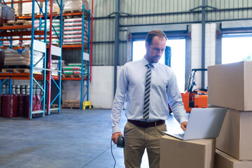 Managing inventory in warehouse, businessman using laptop and barcode scanner efficiently, copy spac