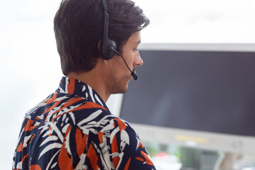 Customer service representative wearing headset assisting clients at office desk, copy space