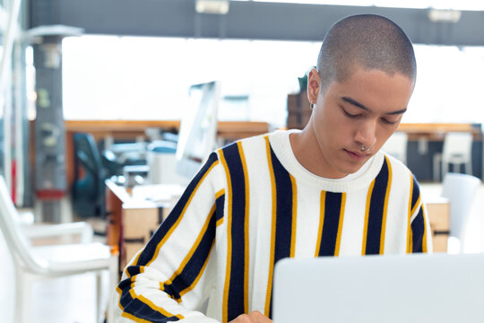 Young man concentrating on laptop work in modern office environment, copy space