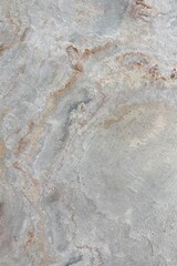 Natural stone texture with earthy tones of gray and rusty orange, showcasing rough surface patterns and organic details, ideal for backgrounds or design elements.