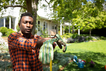 Man in garden putting on gloves, preparing for outdoor gardening work