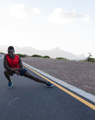 Man stretching on road in nature, preparing for outdoor workout, feeling energized, copy space