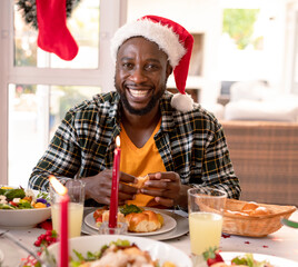 Smiling man in Santa hat enjoying festive meal at home with family