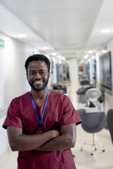 Smiling healthcare professional in scrubs standing confidently in hospital corridor