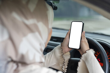 Muslim women holding smartphone with white blank screen while driving, suitable for mobile app...