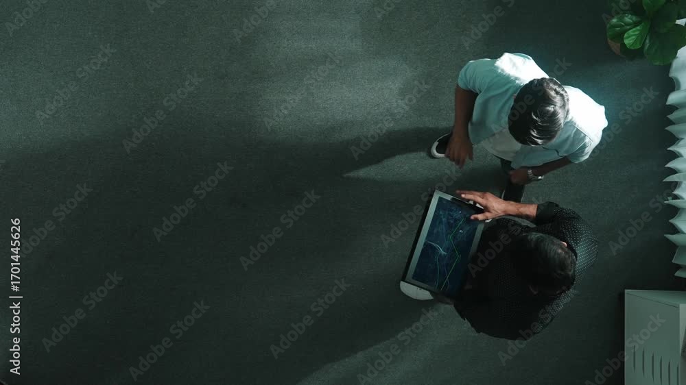 Poster top down view of manager stand with investor while holding tablet and looking at financial statistic