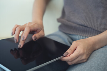 Close up, woman hand using digital tablet at home, finger touching on screen. Freelancer remote...