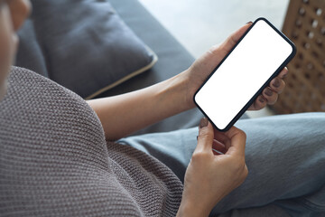 Mockup woman's hand holding using smart phone with white blank screen at coffee shop, mobile app design and advertising, online marketing, close up