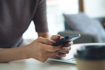 Close up, woman using mobile phone, social media network, online shopping and  mobile banking with laptop computer on table at home. Freelancer woman surfing the internet, remote working