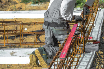
Close-up of worker's hands in gloves, who is tying reinforcement for foundation reinforcement.
