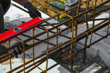 
Close-up of worker's hands in gloves, who is tying reinforcement for foundation reinforcement.
