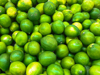 A full frame close-up shot of a large pile of fresh green limes, highlighting their vibrant color, rough texture, and natural freshness. Perfect for food, healthy eating, and natural themes.