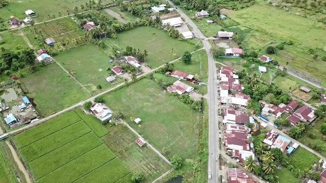 Aerial drone view of Kampung Baru SP2, Nabire, Central Papua, showing village houses, rice fields, farmland, and lush tropical greenery in a rural countryside setting.