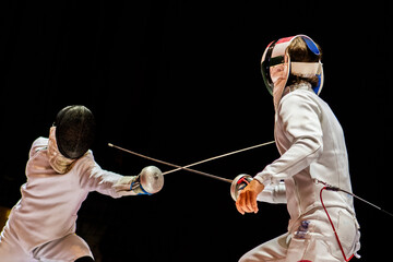 Two fencing athletes fight on professional sports arena