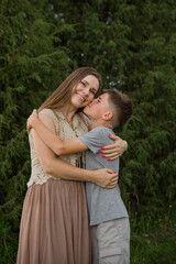 Fototapeta premium A loving son kisses his happy mother on the cheek. The concept of family, the relationship between mother and son