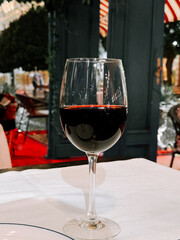 Wine glass filled with red wine on a table in a cozy restaurant setting at night
